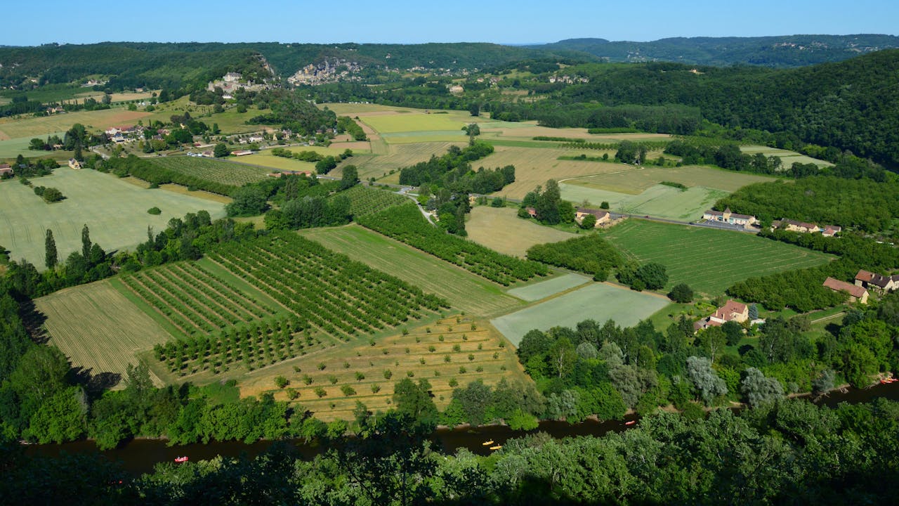 A stunning aerial view of lush countryside fields and farms under a bright summer sky.